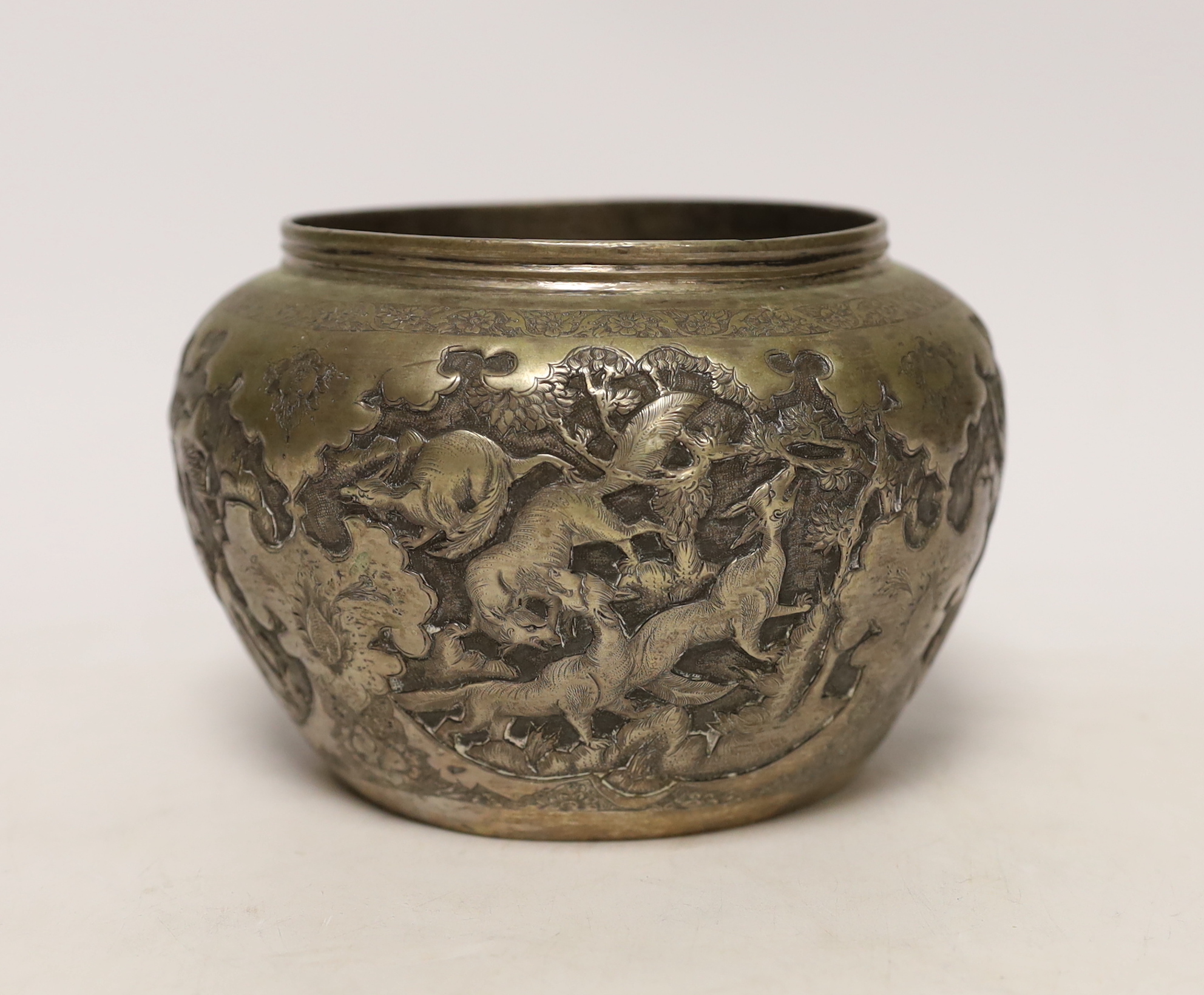 A Persian white metal bowl decorated in relief with animals and flowers, indistinct marks to the base, 16cm wide